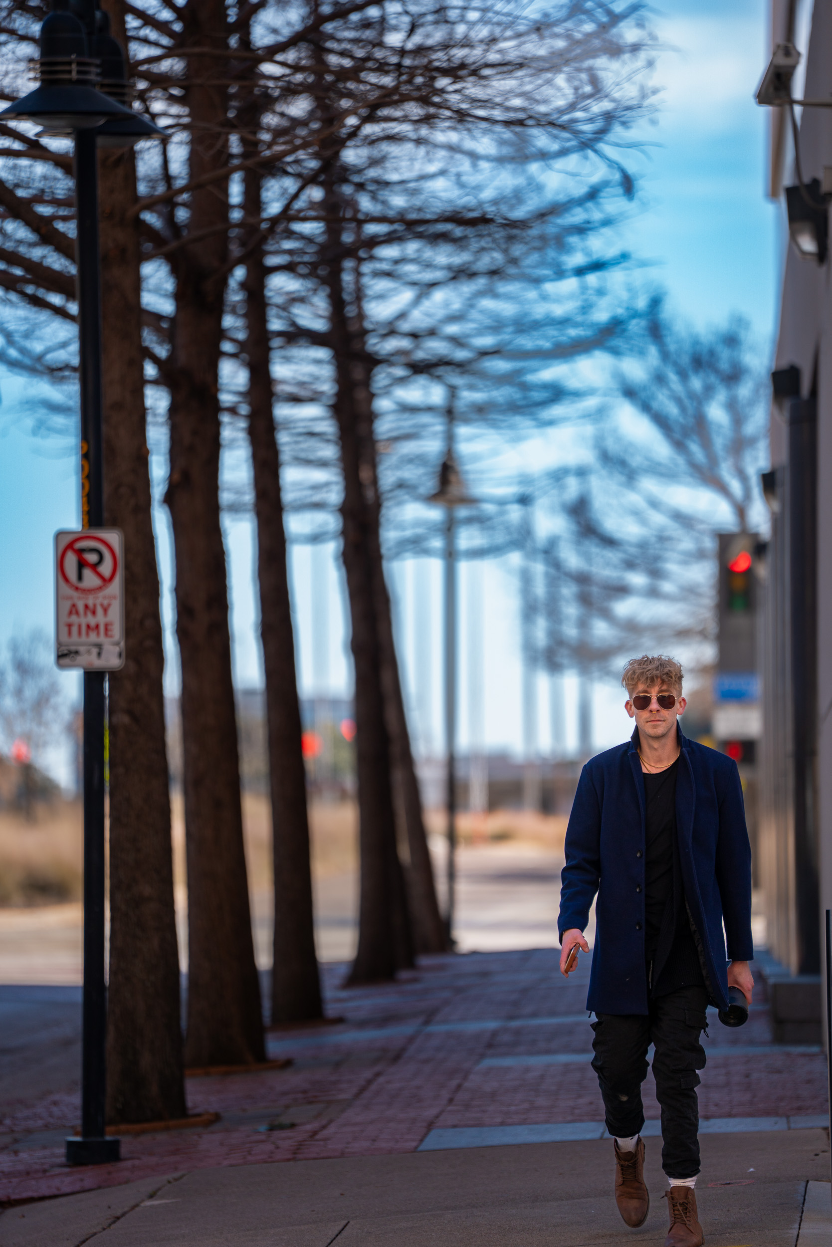 Man in a blue coat walking a city sidewalk