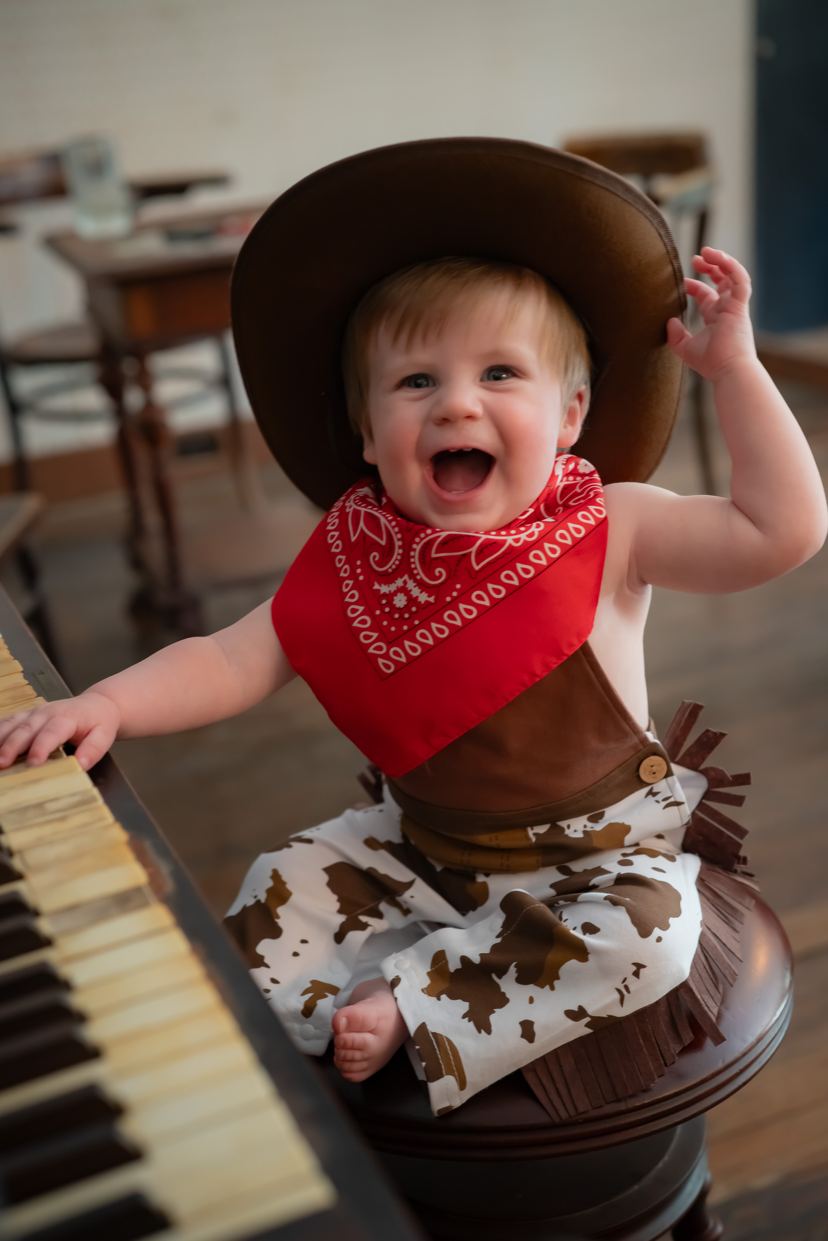 Toddler in a cowboy hat at a piano